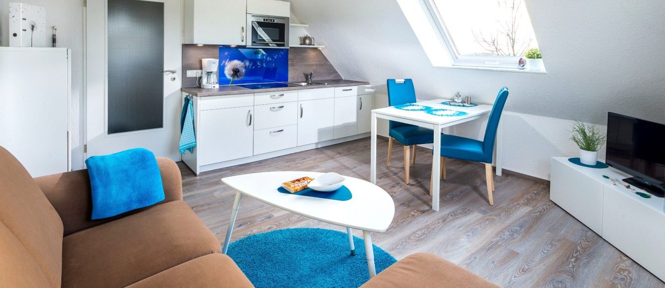 Heller Wohn- und Essbereich mit Küchenzeile der Ferienwohnung Tillmanns Pusteblume in Norddeich an der Nordsee.