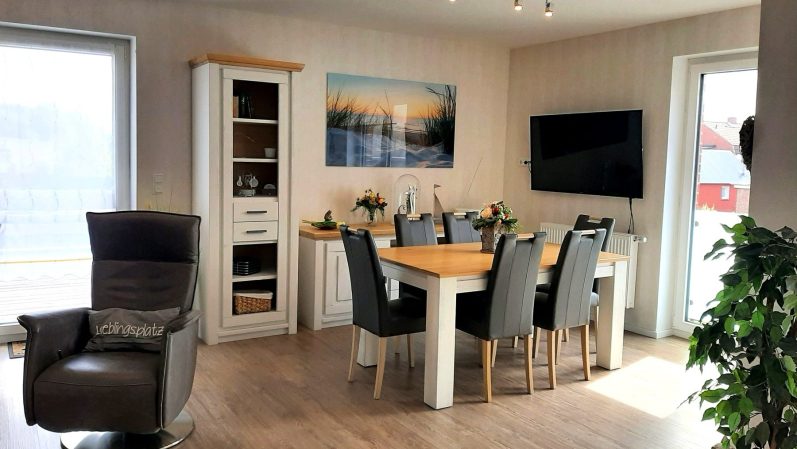 Heller Wohn- und Essbereich mit Tisch, Stühlen und großen Fenstern.